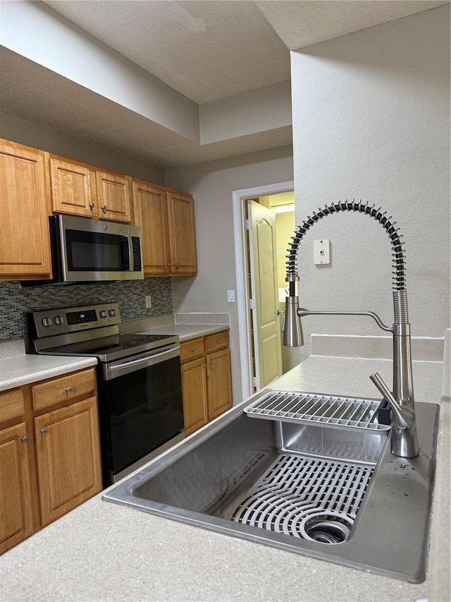 kitchen featuring stainless steel appliances, backsplash, and sink