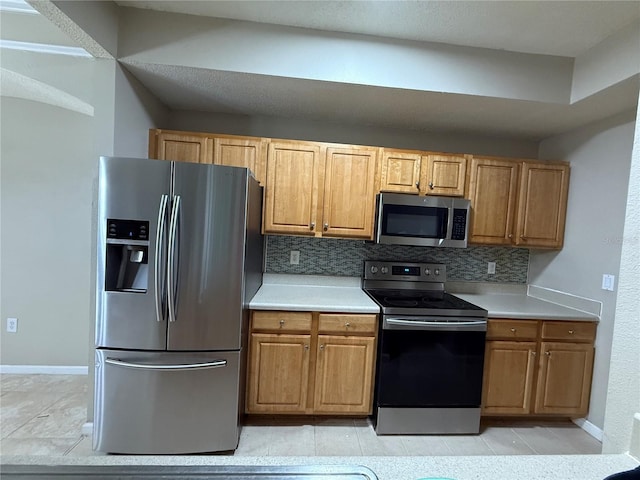 kitchen featuring stainless steel appliances, light tile patterned flooring, and backsplash