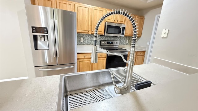 kitchen featuring stainless steel appliances, light brown cabinets, and backsplash