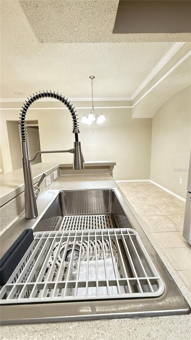 interior details featuring sink, decorative light fixtures, a textured ceiling, a chandelier, and crown molding