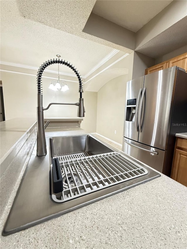 room details featuring a notable chandelier, a textured ceiling, stainless steel fridge, and sink