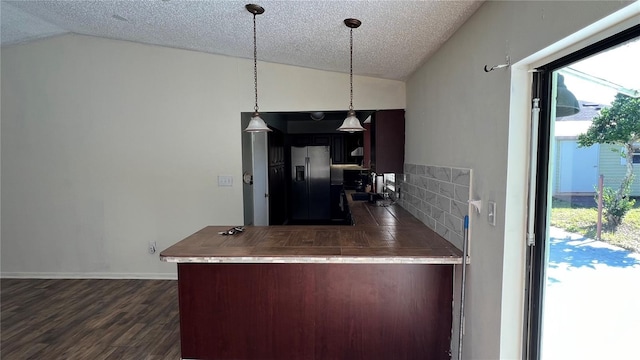 kitchen with stainless steel fridge, dark hardwood / wood-style floors, tasteful backsplash, a textured ceiling, and vaulted ceiling