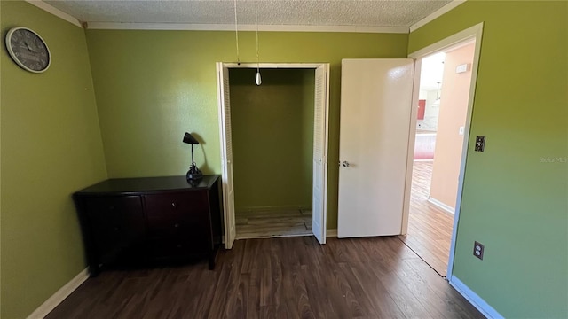 unfurnished bedroom featuring crown molding, dark wood-type flooring, a textured ceiling, and a closet