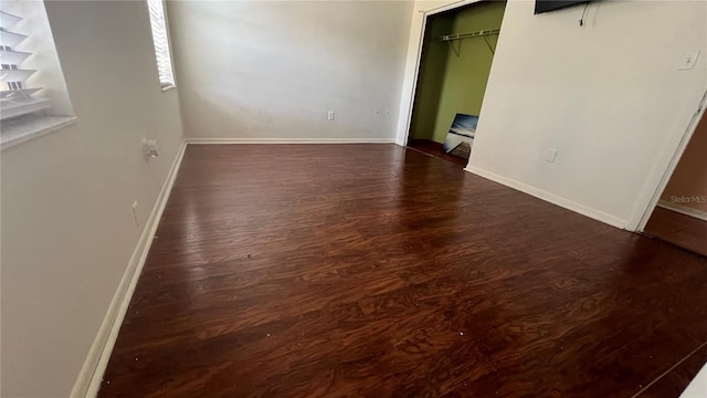 unfurnished bedroom featuring dark wood-style flooring, baseboards, and a closet