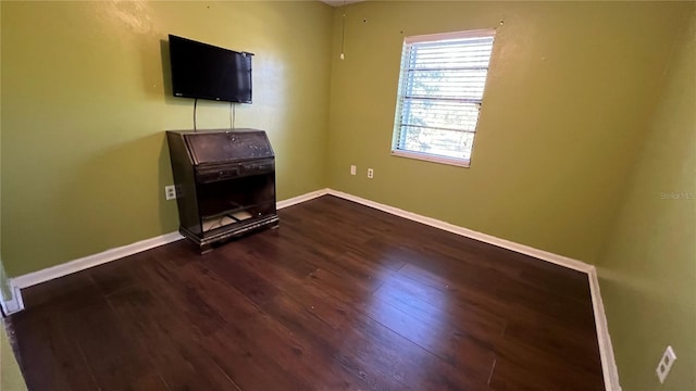 unfurnished living room with dark wood-type flooring and baseboards
