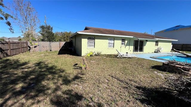 back of property featuring a fenced backyard, a fenced in pool, a yard, and concrete block siding
