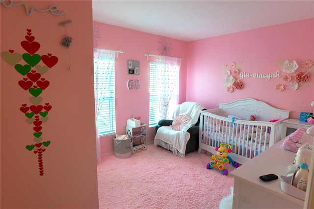 bedroom with multiple windows, carpet floors, and a crib