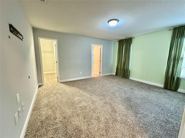 unfurnished bedroom featuring a walk in closet, carpet flooring, a textured ceiling, and a closet