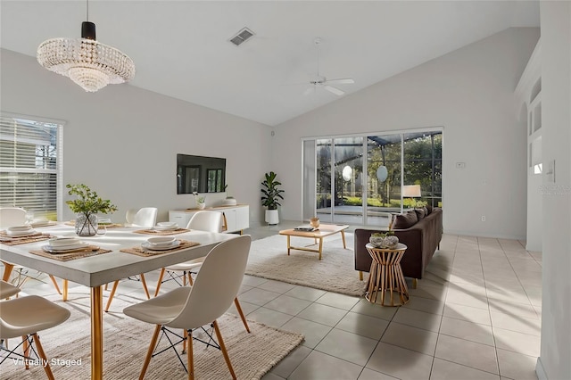 dining space with light tile patterned floors, ceiling fan with notable chandelier, and high vaulted ceiling