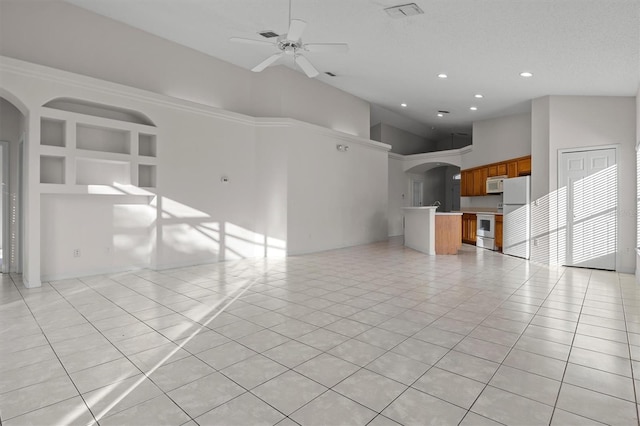 unfurnished living room with a textured ceiling, a towering ceiling, ceiling fan, and light tile patterned flooring