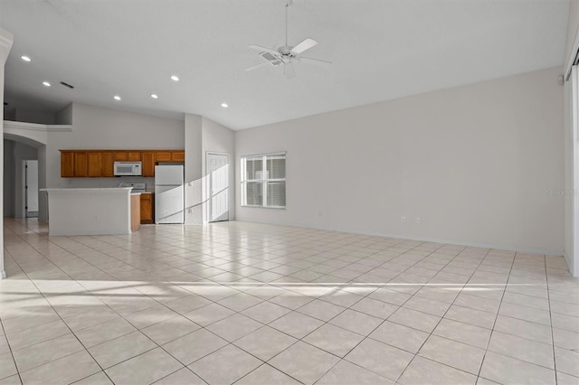 unfurnished living room with ceiling fan, light tile patterned floors, and high vaulted ceiling