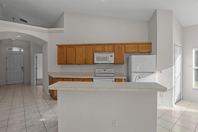 kitchen featuring white appliances, a center island, high vaulted ceiling, and light tile patterned flooring