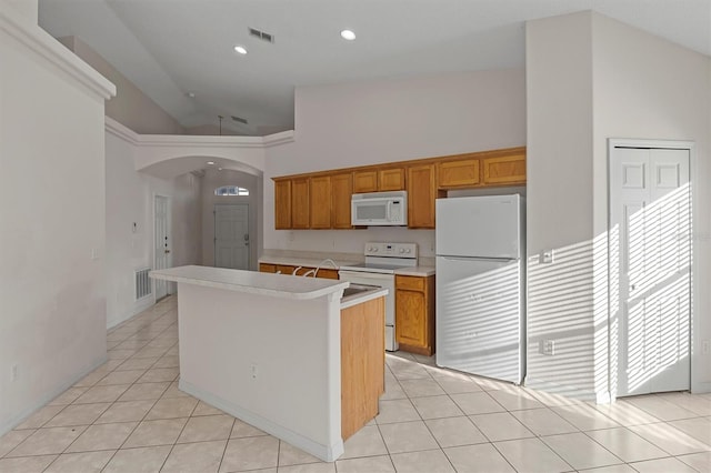 kitchen with light tile patterned floors, white appliances, a center island, and high vaulted ceiling