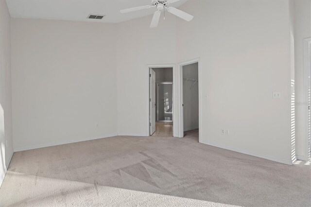 carpeted spare room featuring a towering ceiling and ceiling fan