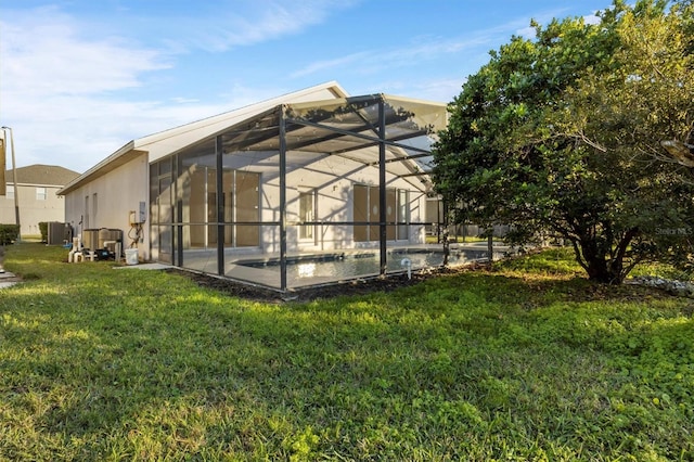 back of property featuring glass enclosure and a lawn