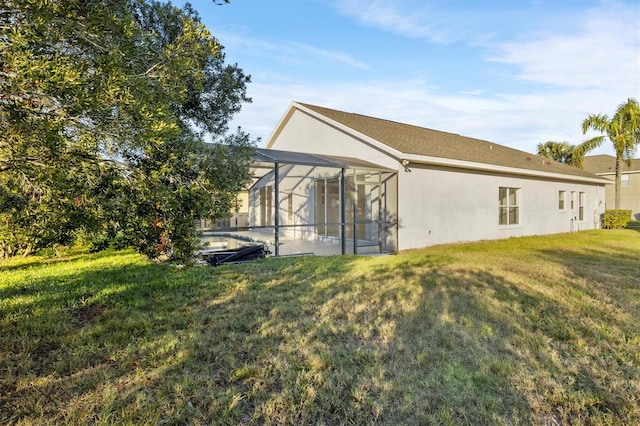 back of property featuring a yard, glass enclosure, and a patio area