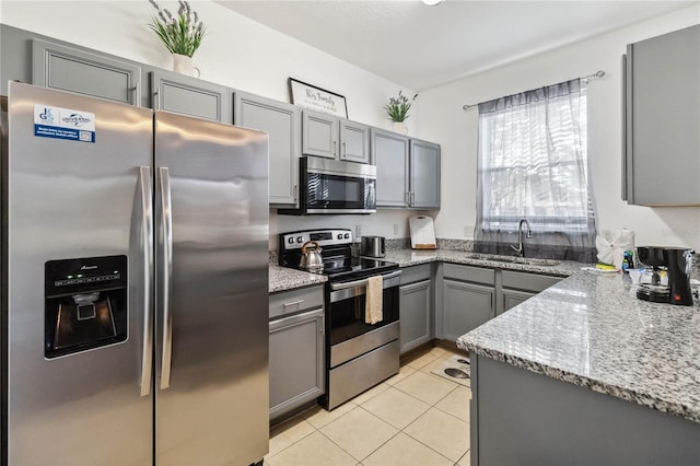 kitchen featuring gray cabinetry, sink, light stone counters, light tile patterned floors, and appliances with stainless steel finishes