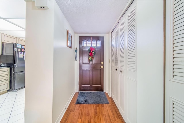 doorway with a textured ceiling and light hardwood / wood-style flooring