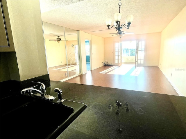 workout room featuring a textured ceiling, ceiling fan with notable chandelier, and sink