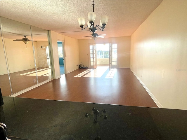 interior space with ceiling fan with notable chandelier, hardwood / wood-style floors, and a textured ceiling