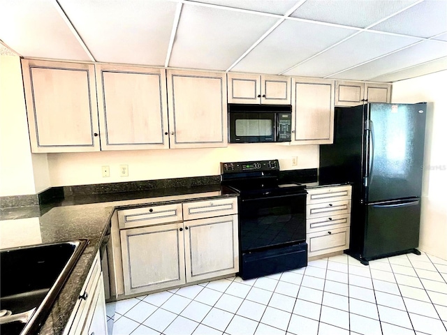 kitchen with a drop ceiling, light tile patterned floors, black appliances, and sink