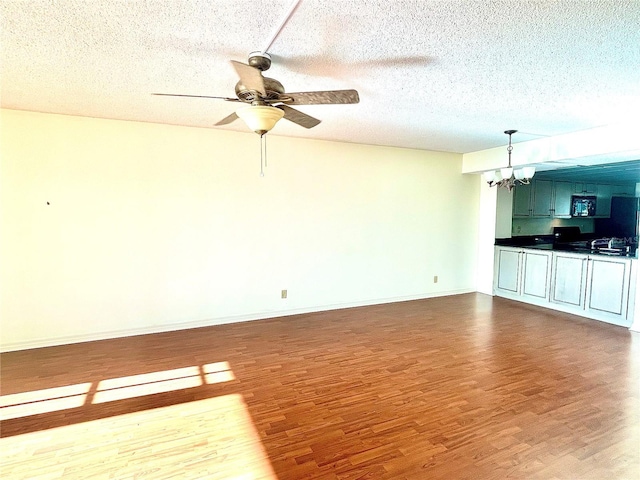 unfurnished living room with hardwood / wood-style floors, ceiling fan with notable chandelier, and a textured ceiling