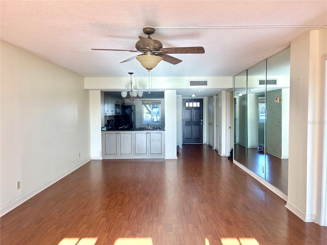 unfurnished living room featuring dark hardwood / wood-style flooring, sink, and a textured ceiling