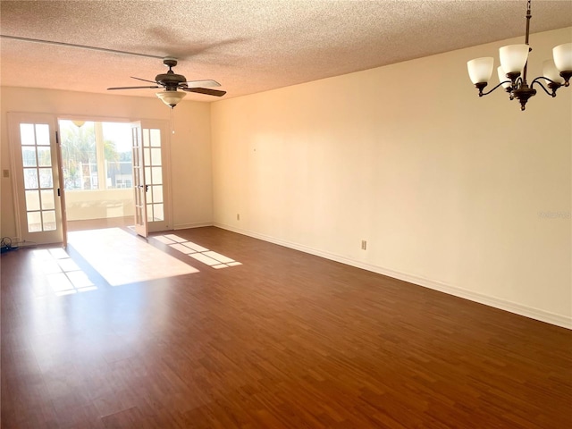 spare room with ceiling fan with notable chandelier, french doors, dark hardwood / wood-style flooring, and a textured ceiling