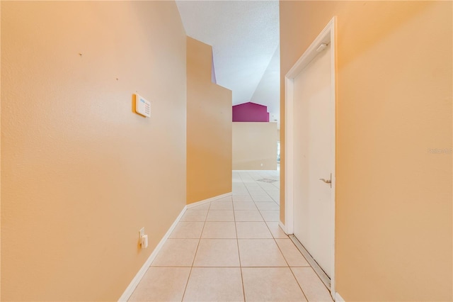 corridor featuring light tile patterned flooring and lofted ceiling