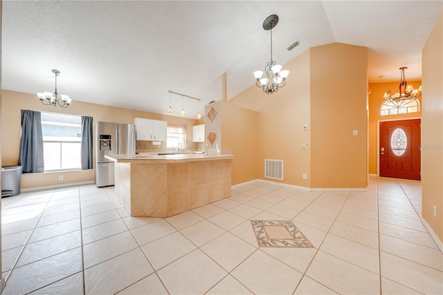 kitchen with light tile patterned floors, a chandelier, stainless steel fridge with ice dispenser, and kitchen peninsula