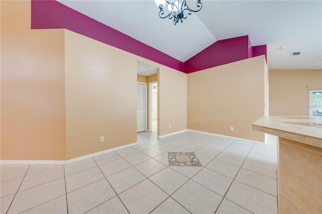 tiled empty room featuring a chandelier and vaulted ceiling