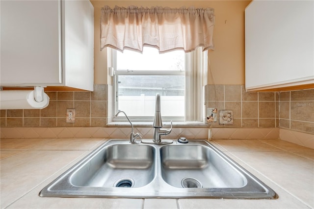 kitchen featuring white cabinetry, sink, and tasteful backsplash