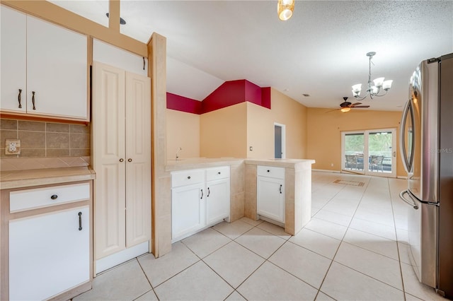 kitchen with lofted ceiling, white cabinetry, stainless steel fridge, kitchen peninsula, and hanging light fixtures