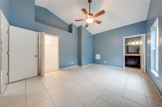 unfurnished bedroom with vaulted ceiling, a walk in closet, ensuite bath, light tile patterned flooring, and ceiling fan