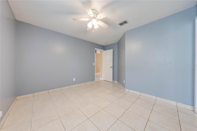 empty room featuring a textured ceiling, ceiling fan, and light tile patterned floors