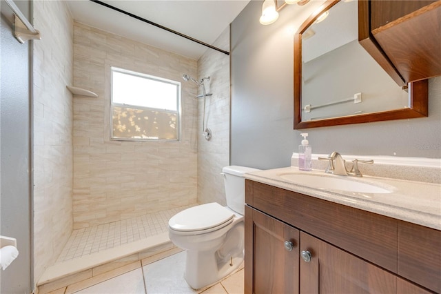 bathroom with tile patterned floors, tiled shower, vanity, and toilet