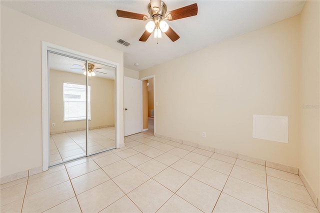 unfurnished bedroom featuring ceiling fan, light tile patterned floors, and a closet