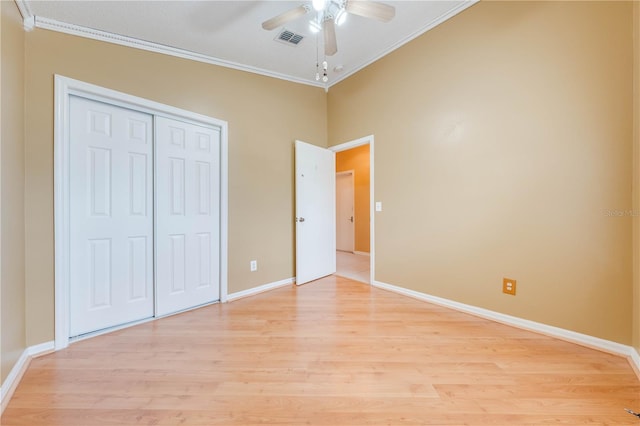 unfurnished bedroom featuring light hardwood / wood-style flooring, crown molding, and a closet