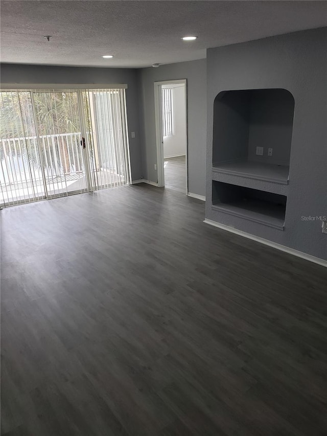 unfurnished living room with dark hardwood / wood-style flooring and a textured ceiling