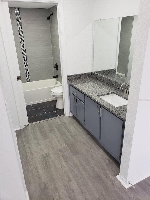 full bathroom featuring hardwood / wood-style flooring, vanity, toilet, and tiled shower / bath