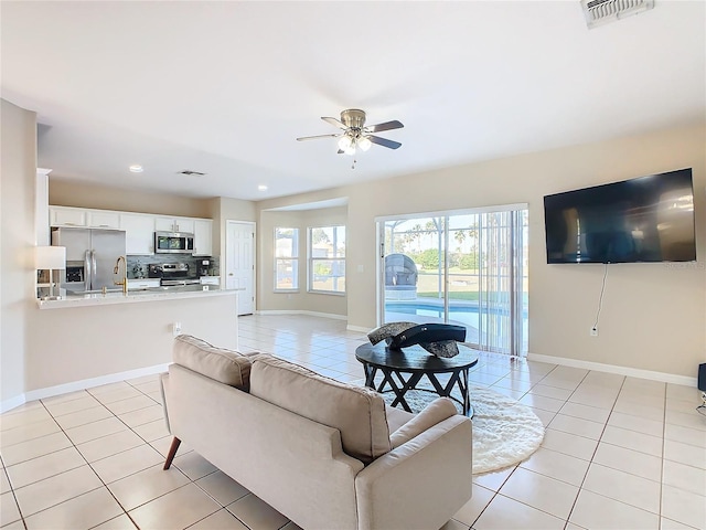 tiled living room featuring ceiling fan and sink