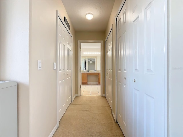 corridor featuring washer / dryer and light colored carpet