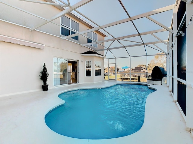 view of swimming pool with glass enclosure and a patio