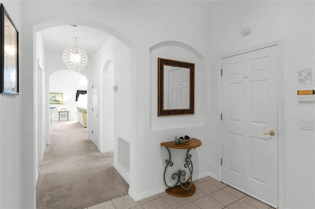 hall featuring light colored carpet and a notable chandelier