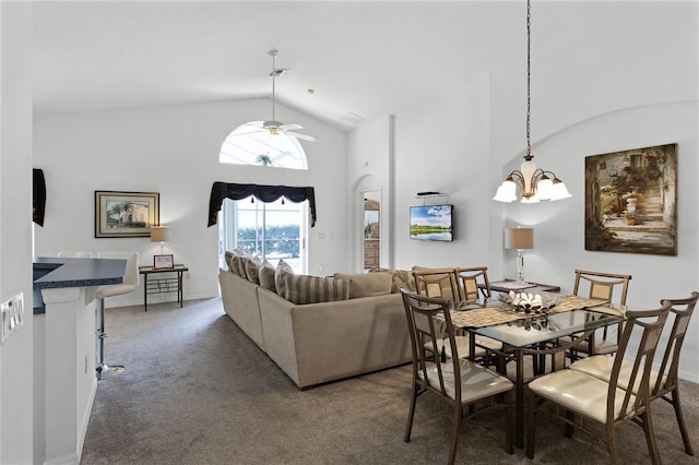 dining room with high vaulted ceiling, ceiling fan with notable chandelier, and dark colored carpet