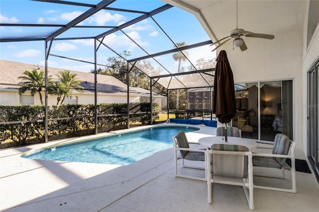 view of swimming pool with a patio, glass enclosure, and ceiling fan