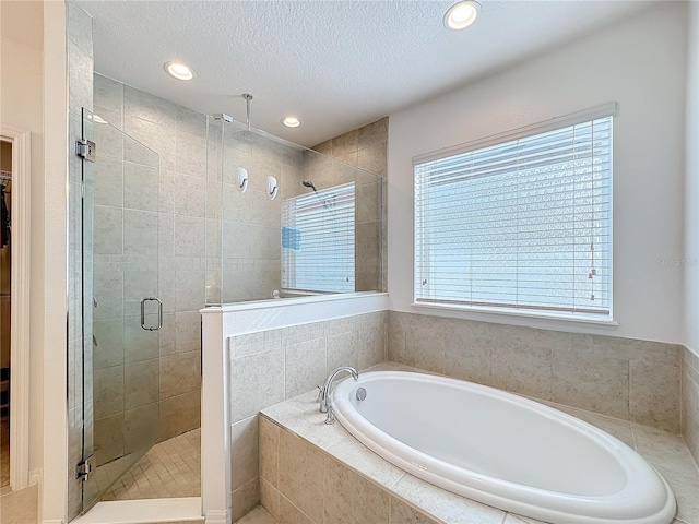 bathroom featuring separate shower and tub and a textured ceiling