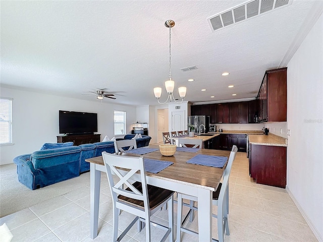 tiled dining room featuring plenty of natural light, ceiling fan with notable chandelier, a textured ceiling, and sink