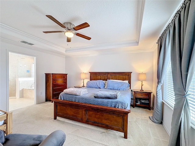 carpeted bedroom with a raised ceiling, ceiling fan, crown molding, and ensuite bathroom