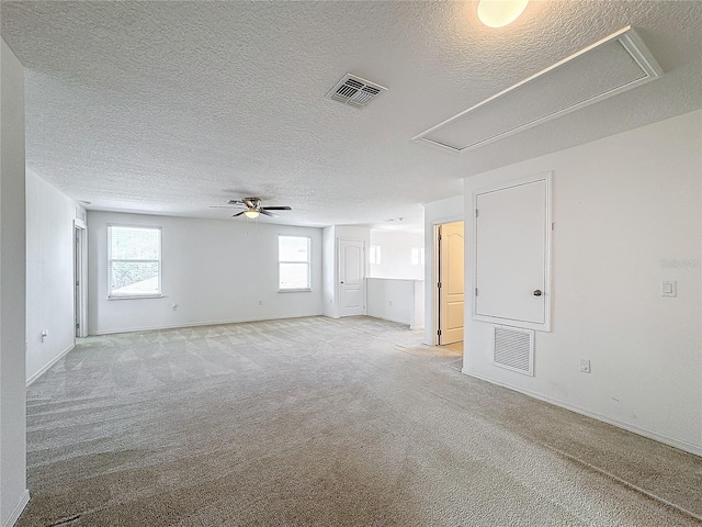 empty room with ceiling fan, light colored carpet, and a textured ceiling